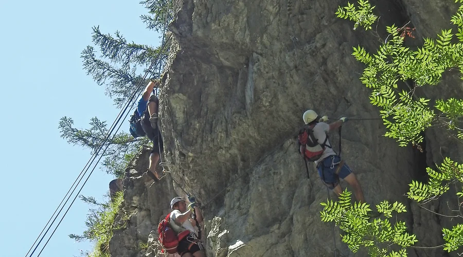 Klettersteiggeher an einer drahtseilversicherten Felswand in der Kitzlochklamm bei Taxenbach, Land Salzburg, mit deutlich sichtbarer Ausgesetztheit